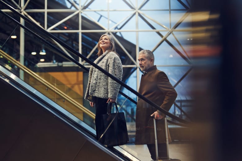 par á leið upp rúllustiga í flugstöð